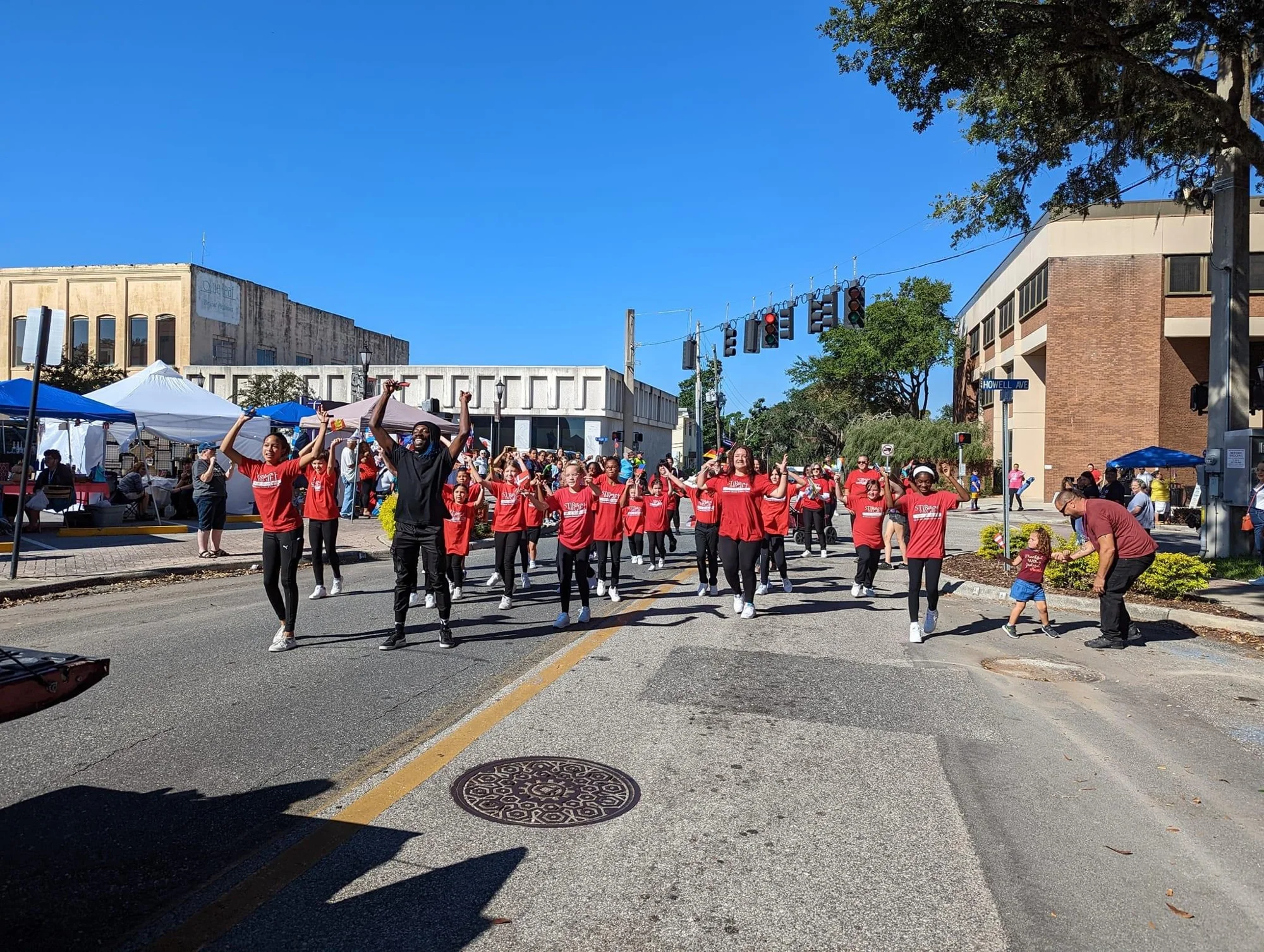 Stir Up The Gift dancers in red studio shirts performing together in downtown Brooksville
